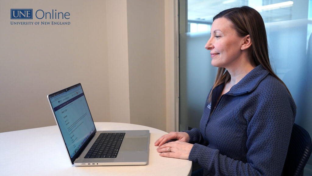 side view from an external webcam for taking exams with a woman sitting in front of a laptop with her hands on the table